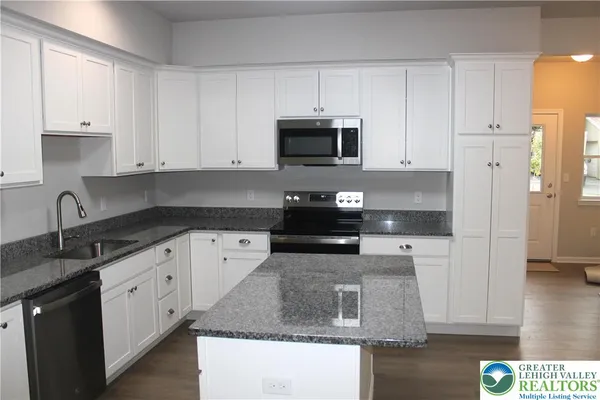 a kitchen with stainless steel appliances granite countertop a sink a stove and a refrigerator
