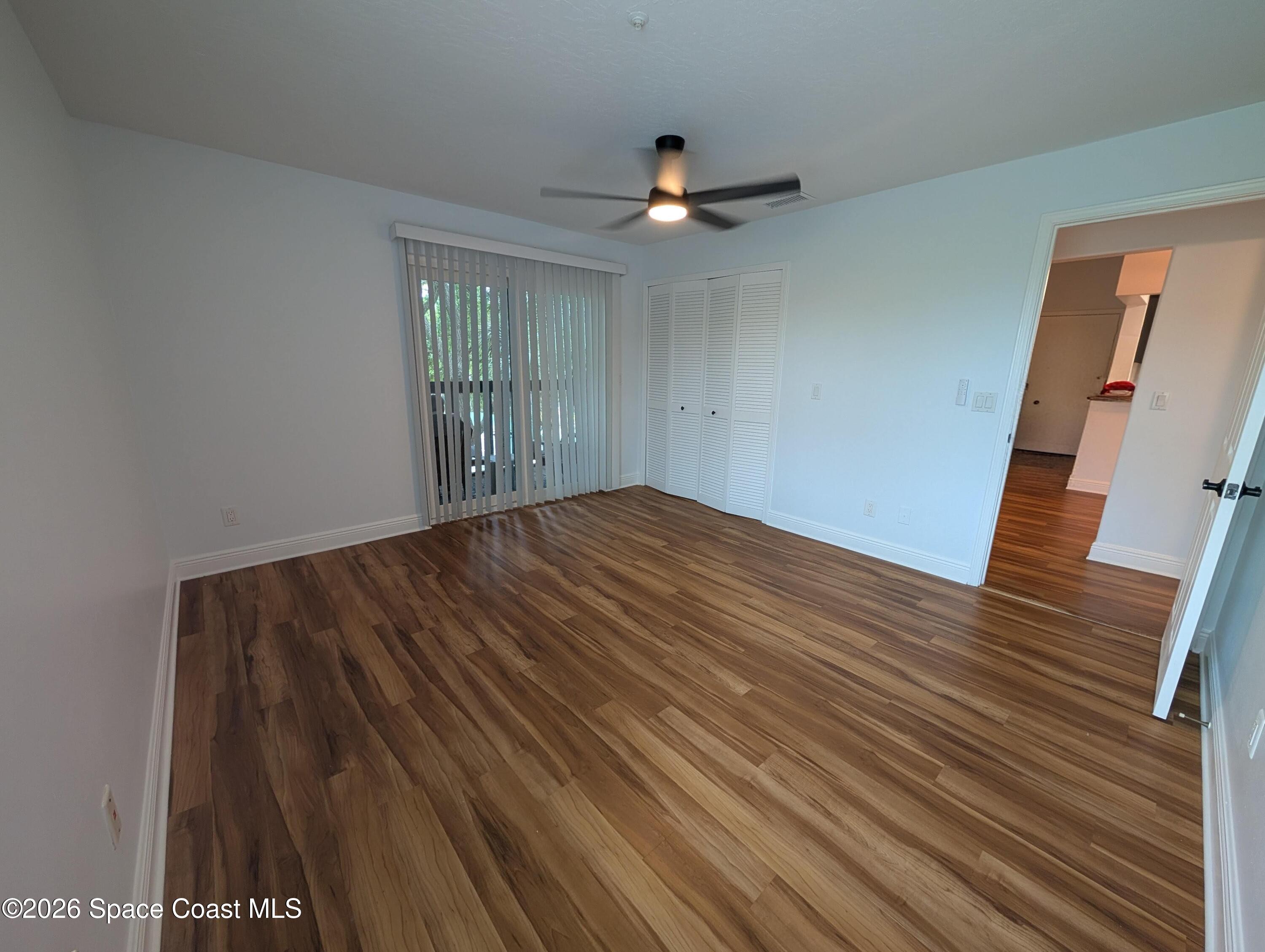 7667 North Wickham Road, Unit 818 Melbourne, FL 32940 - Photo 11 of 29 a view of an empty room with wooden floor and a ceiling fan
