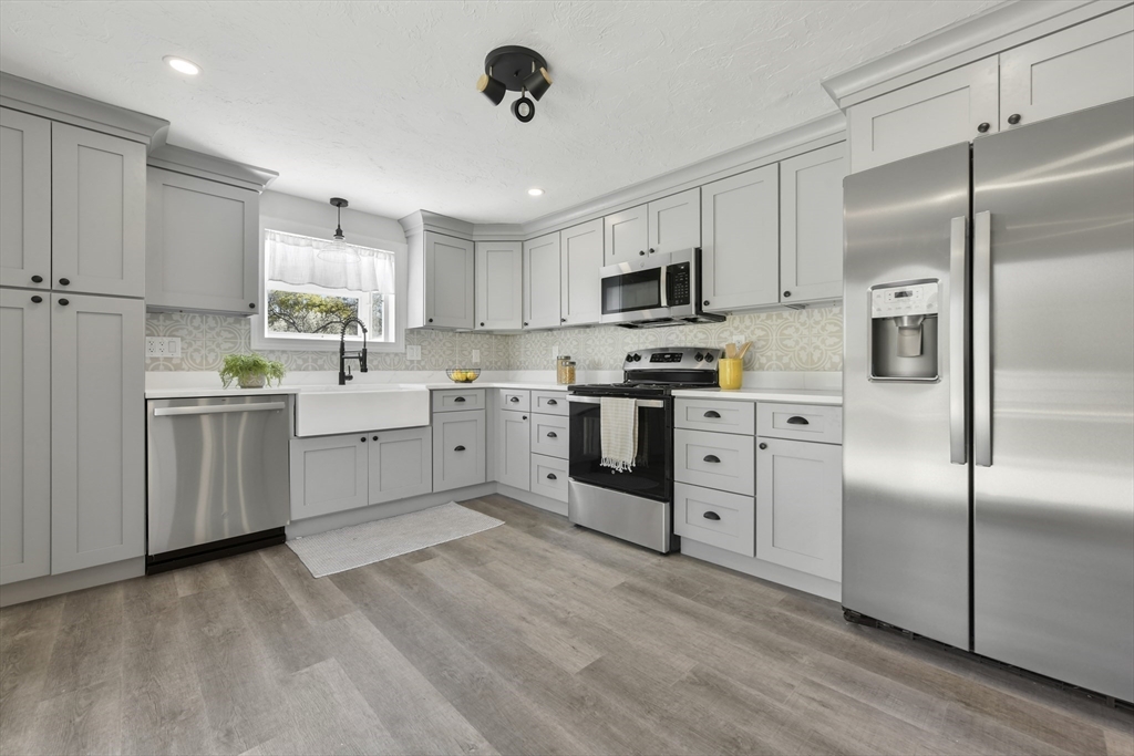 a kitchen with white cabinets stainless steel appliances and a refrigerator