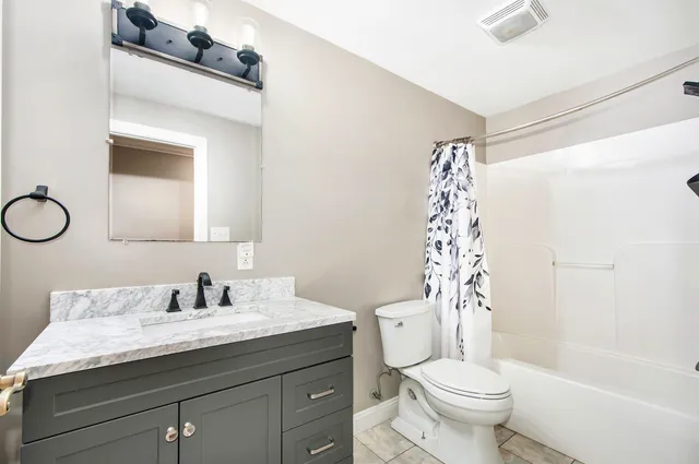 a bathroom with a sink a toilet a mirror a vanity and shower