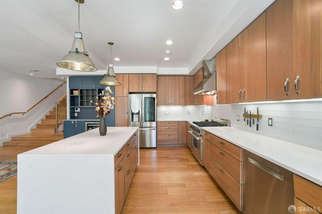 a kitchen with stainless steel appliances kitchen island a sink and a refrigerator