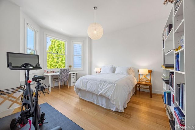 a bedroom with a bed furniture and a flat tv screen on the dresser