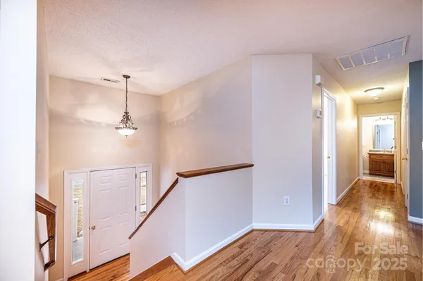 a view of a hallway with wooden floor and staircase