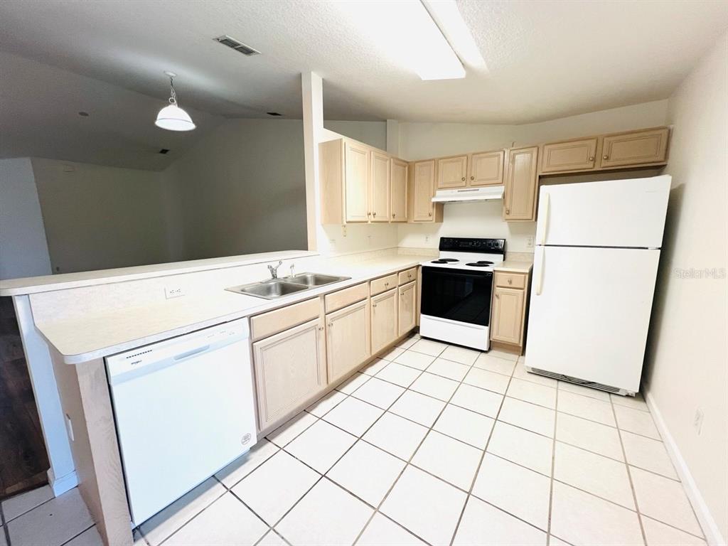 78 Plainview Drive, Unit B Palm Coast, FL 32164 - Photo 2 of 7 a kitchen with a sink a refrigerator and white cabinets