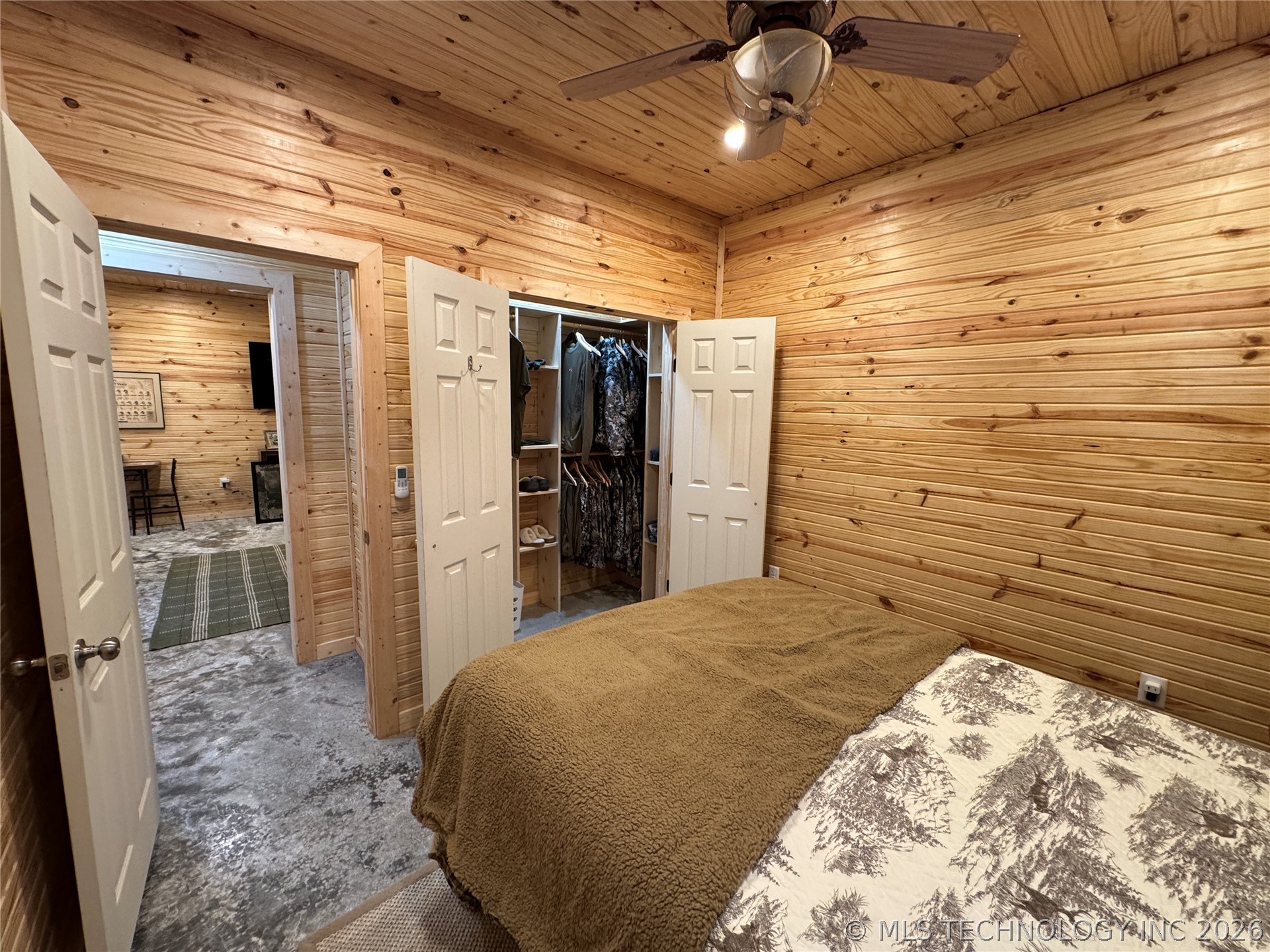 20862 East 1160th Road Keota, OK 74941 - Photo 25 of 47 Wood-paneled room featuring a ceiling fan with integrated lighting, wood-finish walls, and a closet with bifold doors