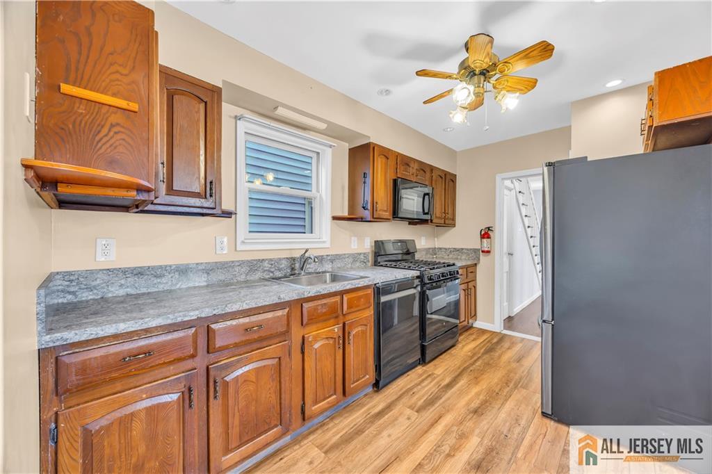 27 Charles Street Carteret, NJ 07008 - Photo 17 of 40 a kitchen with stainless steel appliances granite countertop a stove a sink dishwasher and a refrigerator with wooden floor