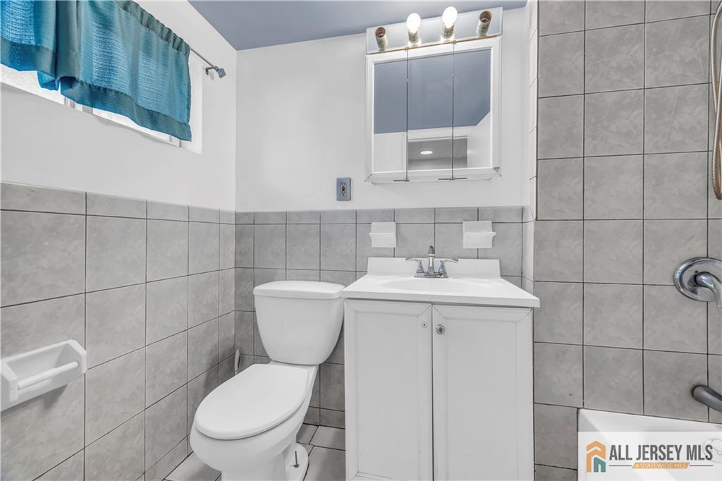 27 Charles Street Carteret, NJ 07008 - Photo 38 of 40 a bathroom with a toilet a sink and mirror