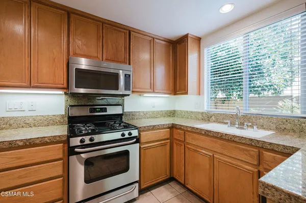 a kitchen with granite countertop cabinets stainless steel appliances a sink and window