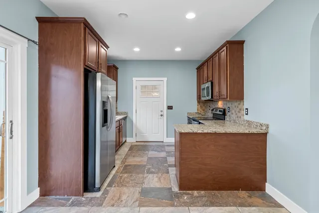 a very nice looking open kitchen with stainless steel appliances granite countertop a refrigerator and a stove