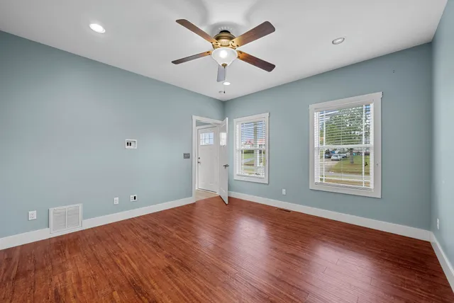 a view of an empty room with wooden floor and a window