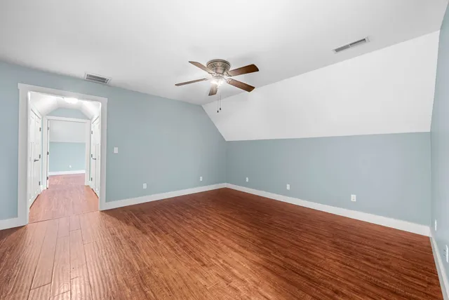 an empty room with wooden floor and fan