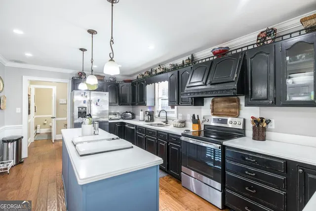 a kitchen with stainless steel appliances granite countertop a sink a stove and a wooden floors