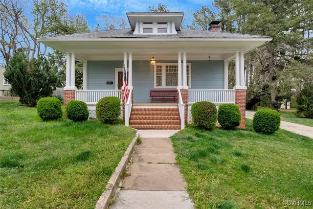 a view of a house with a small yard plants and large trees