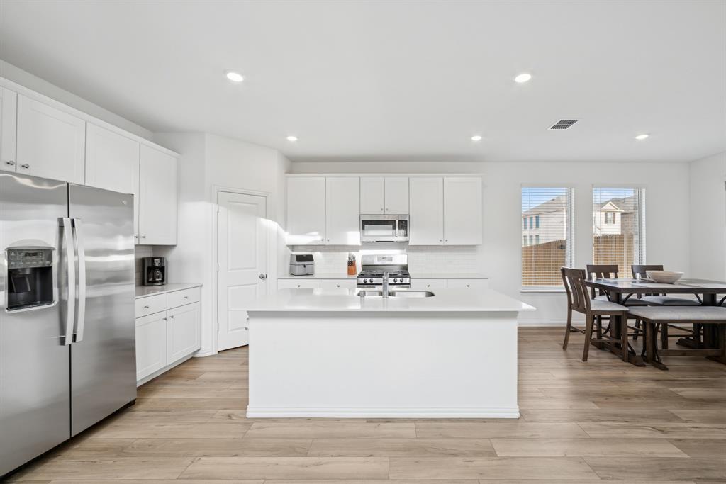 10040 Thornapple Road Fort Worth, TX 76179 - Photo 8 of 24 a living room with stainless steel appliances kitchen island granite countertop a table chairs and a refrigerator