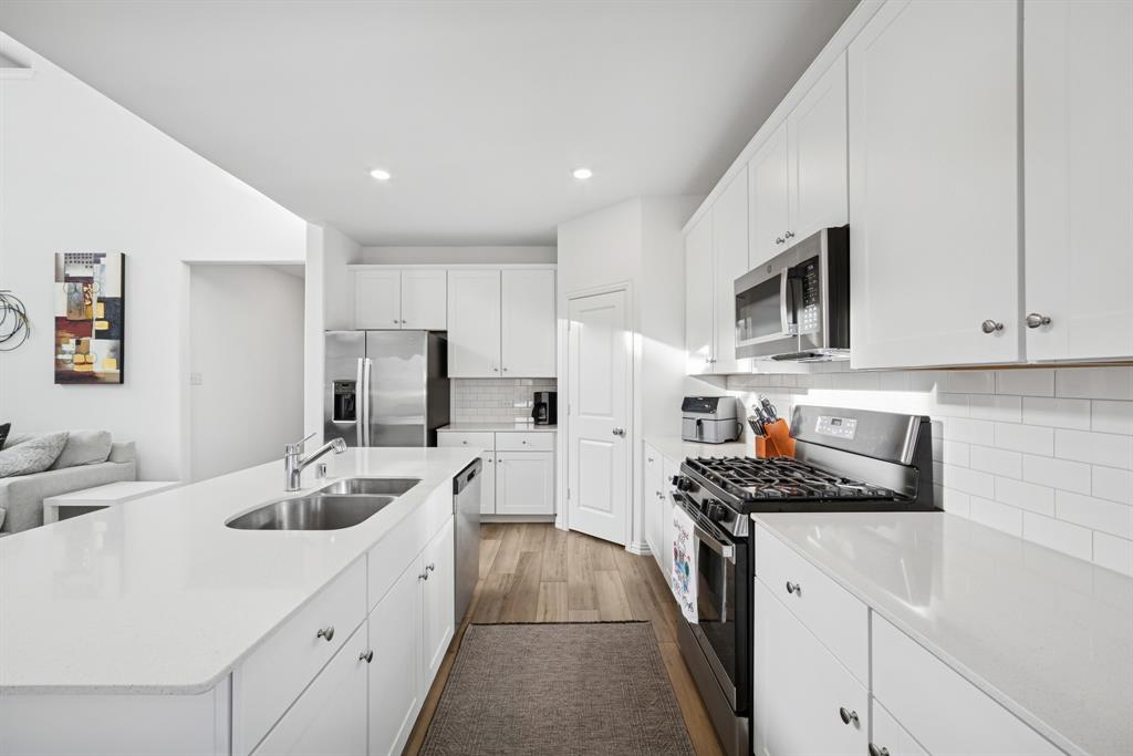 10040 Thornapple Road Fort Worth, TX 76179 - Photo 9 of 24 a kitchen with granite countertop a sink stainless steel appliances and white cabinets