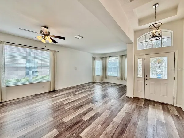 a view of a room with wooden floor chandelier and windows