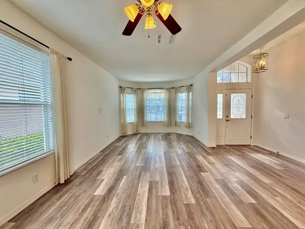 a view of empty room with wooden floor and fan