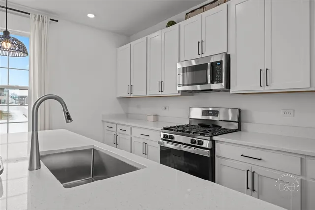 a kitchen with granite countertop white cabinets and stainless steel appliances