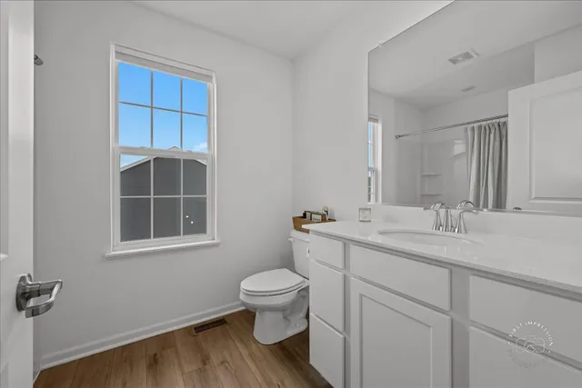 a bathroom with a granite countertop toilet a sink a mirror and a window