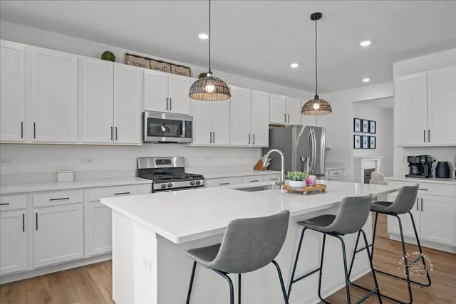 a kitchen with stainless steel appliances kitchen island granite countertop a stove a sink a microwave a dining table and chairs with wooden floor