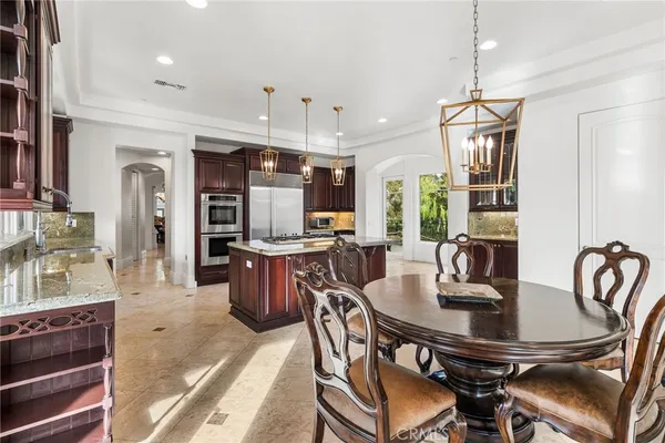 a kitchen with a dining table chairs stainless steel appliances and cabinets