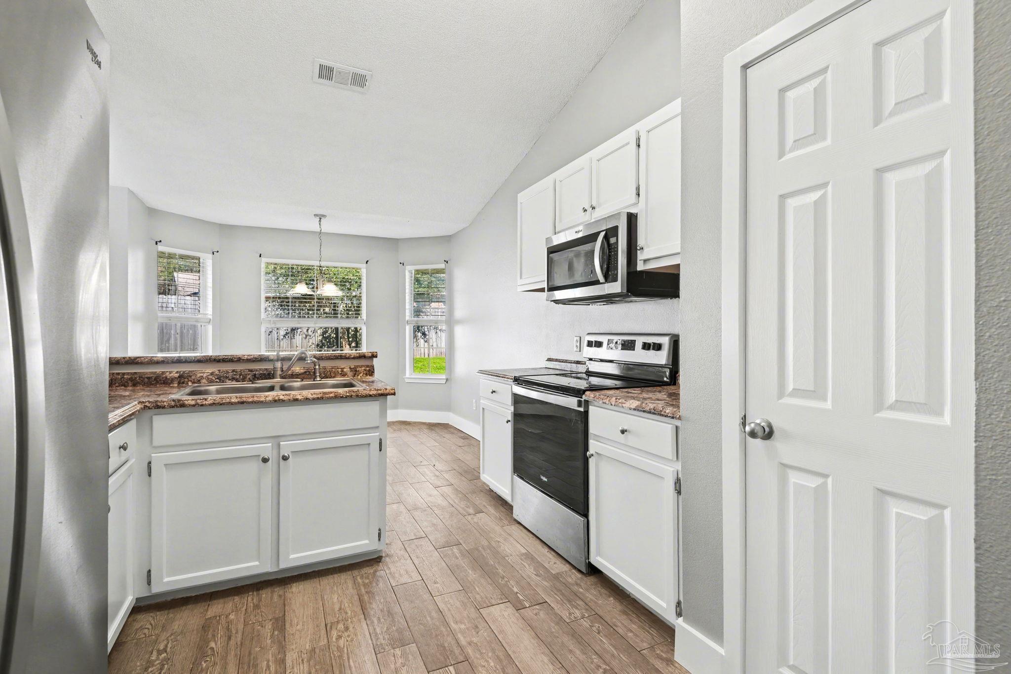 1648 Condor Drive Cantonment, FL 32533 - Photo 20 of 51 a kitchen with stainless steel appliances white cabinets a stove top oven and sink