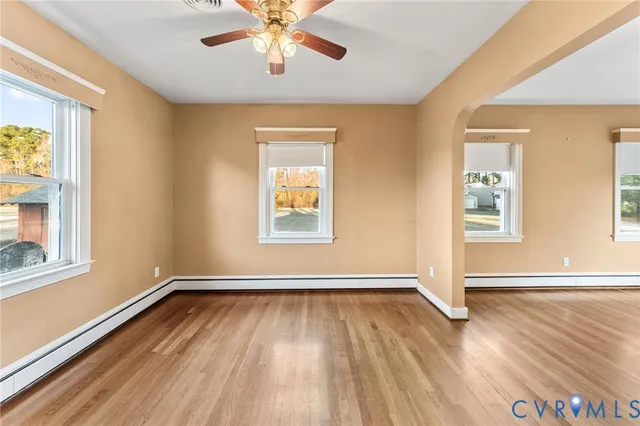 a view of empty room with wooden floor and fan