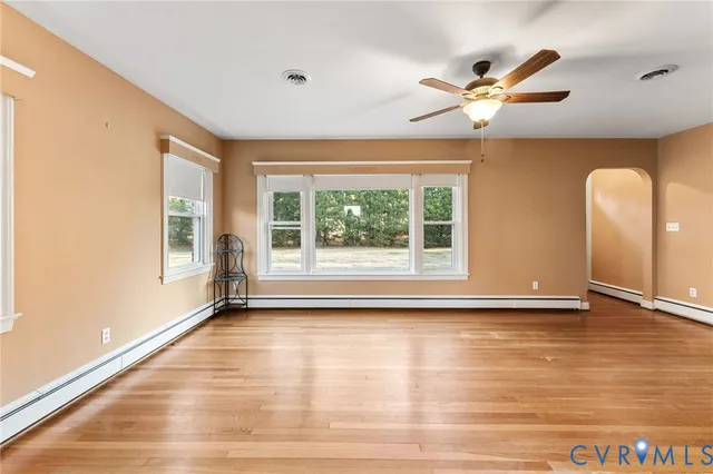 a view of an empty room with a window and wooden floor
