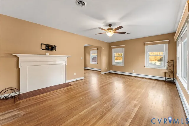 a view of an empty room with window and wooden floor