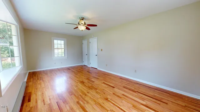 a view of empty room with window and wooden floor