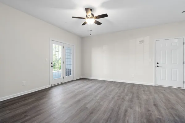 an empty room with wooden floor and chandelier fan