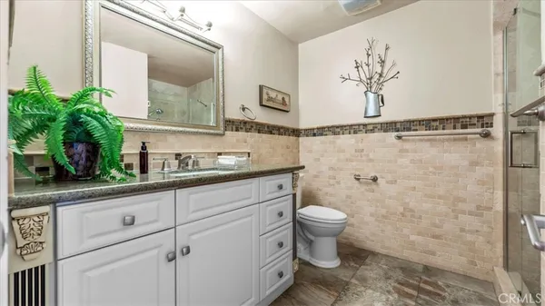 a bathroom with a granite countertop sink a toilet and a mirror