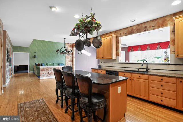 a dining hall with granite countertop a sink dishwasher a dining table and chairs with wooden floor