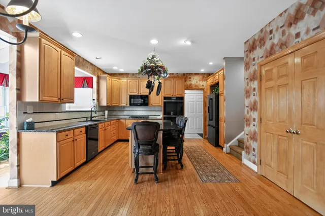 a kitchen with stainless steel appliances kitchen island granite countertop a stove a sink and a refrigerator