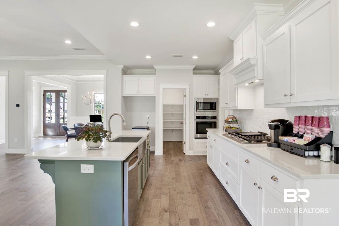 393 Garrison Boulevard Fairhope, AL 36532 - Photo 18 of 40 Kitchen featuring white cabinets, stainless steel appliances, a kitchen island with sink, and light hardwood / wood-style flooring