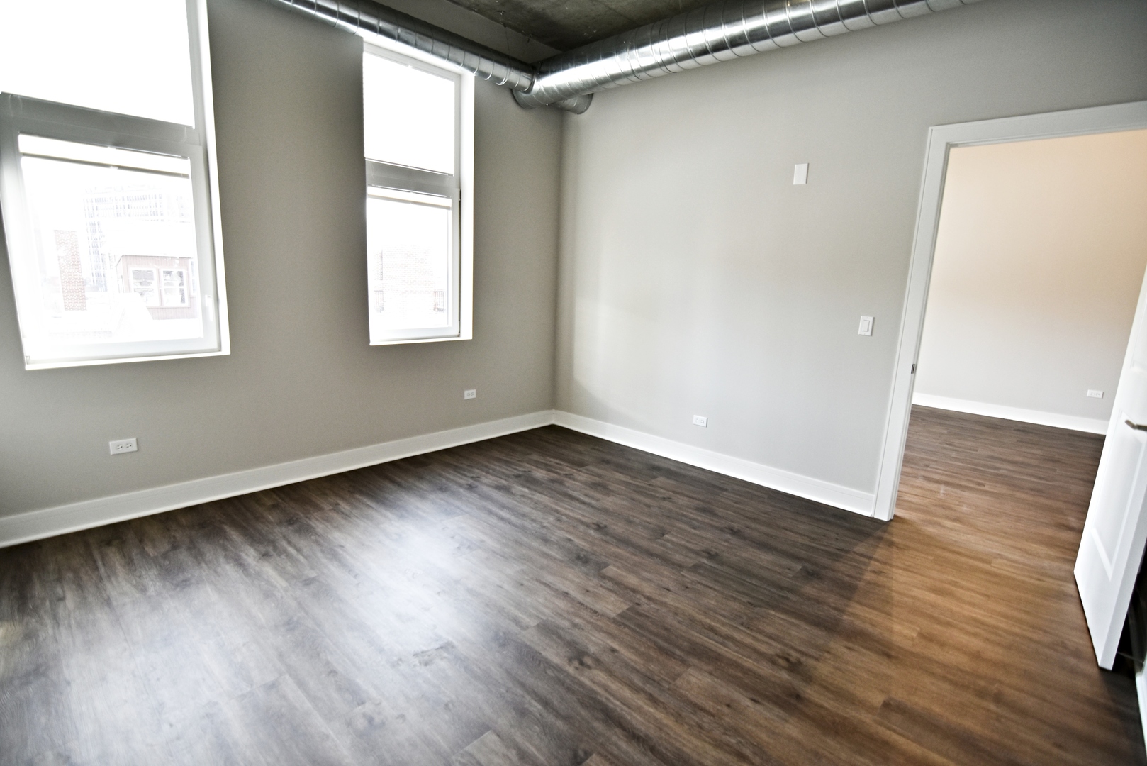 3833 North Broadway, Unit 720 Chicago, IL 60613 - Photo 8 of 11 an empty room with wooden floor and windows
