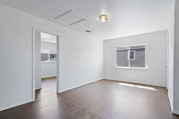 an empty room with wooden floor and windows