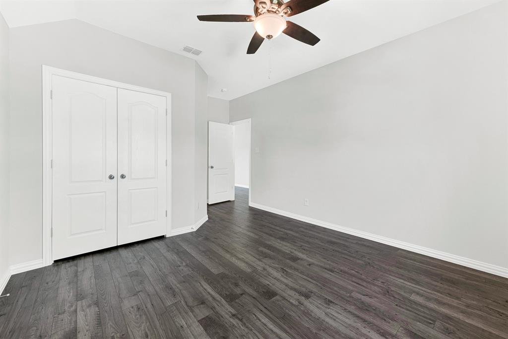 7640 Rhyner Way Fort Worth, TX 76137 - Photo 33 of 40 Spacious bedroom featuring dark wood-finish flooring, white panel double-door closet, ceiling fan with integrated lighting, and clean white walls with generous natural light from multiple windows