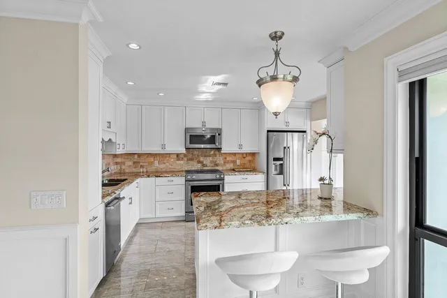 a kitchen with kitchen island granite countertop a white cabinets and refrigerator