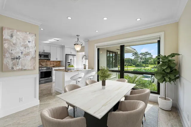 a dining room with furniture a potted plant and open kitchen view