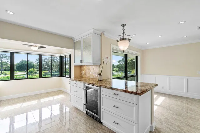 a kitchen with granite countertop a stove a sink and white cabinets with wooden floor