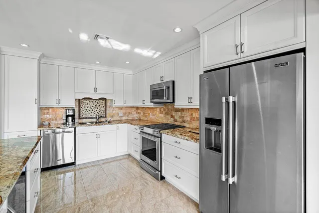 a kitchen with granite countertop a refrigerator stove top oven and sink