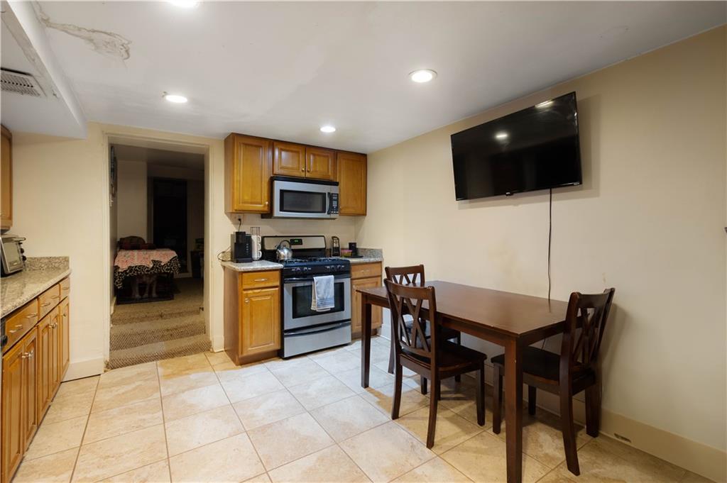 108 Pius Street Pittsburgh, PA 15203 - Photo 7 of 36 a kitchen with stainless steel appliances kitchen island granite countertop a sink a stove a microwave a dining table and chairs