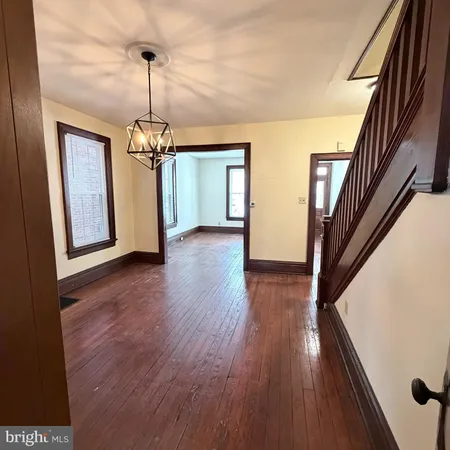 a view of a hallway with wooden floor staircase and a chandelier