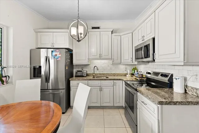 a kitchen with stainless steel appliances granite countertop a sink a stove a refrigerator a washer and dryer
