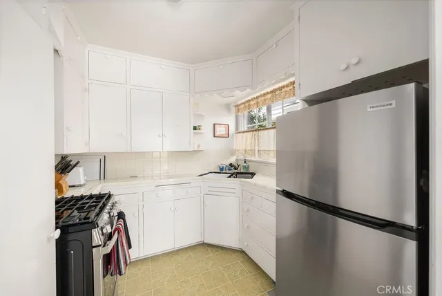 a kitchen with a refrigerator a stove a sink and white cabinets