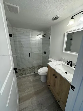 a bathroom with a granite countertop sink toilet and shower