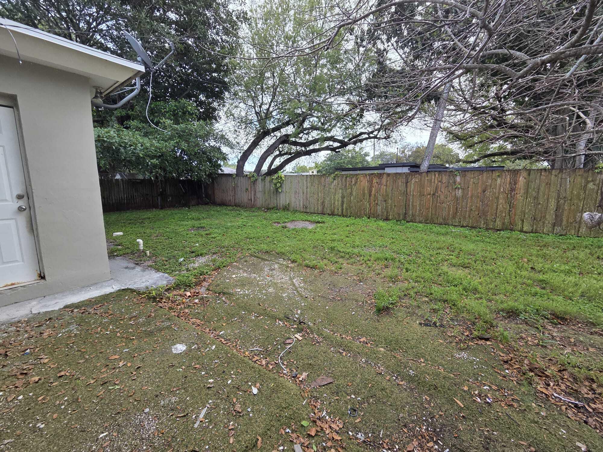 5720 Cleveland Street Hollywood, FL 33021 - Photo 17 of 18 a view of a backyard with large trees and wooden fence
