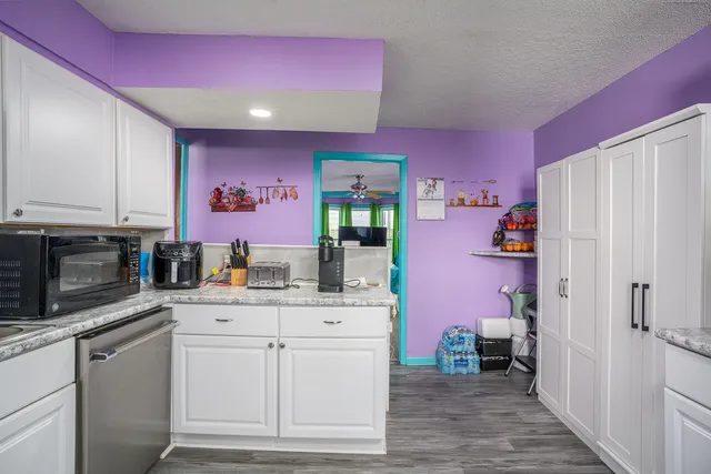 a kitchen with granite countertop a sink cabinets and stainless steel appliances