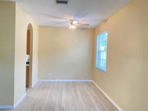 a view of an empty room with chandelier fan and a window